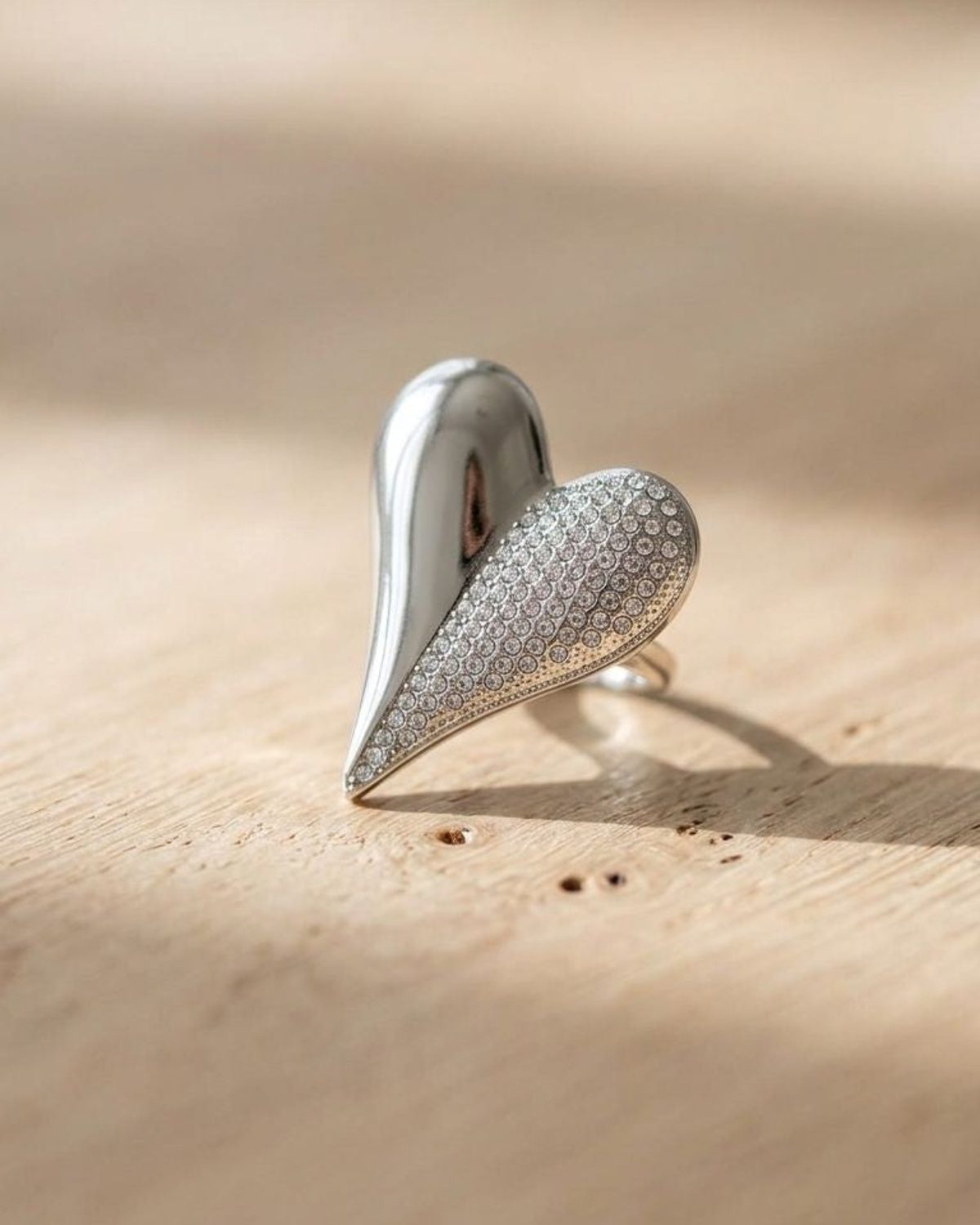 Close-up of the Bold Heart Statement Ring on a natural wood surface, highlighting its asymmetrical heart shape and rhinestone sparkle.