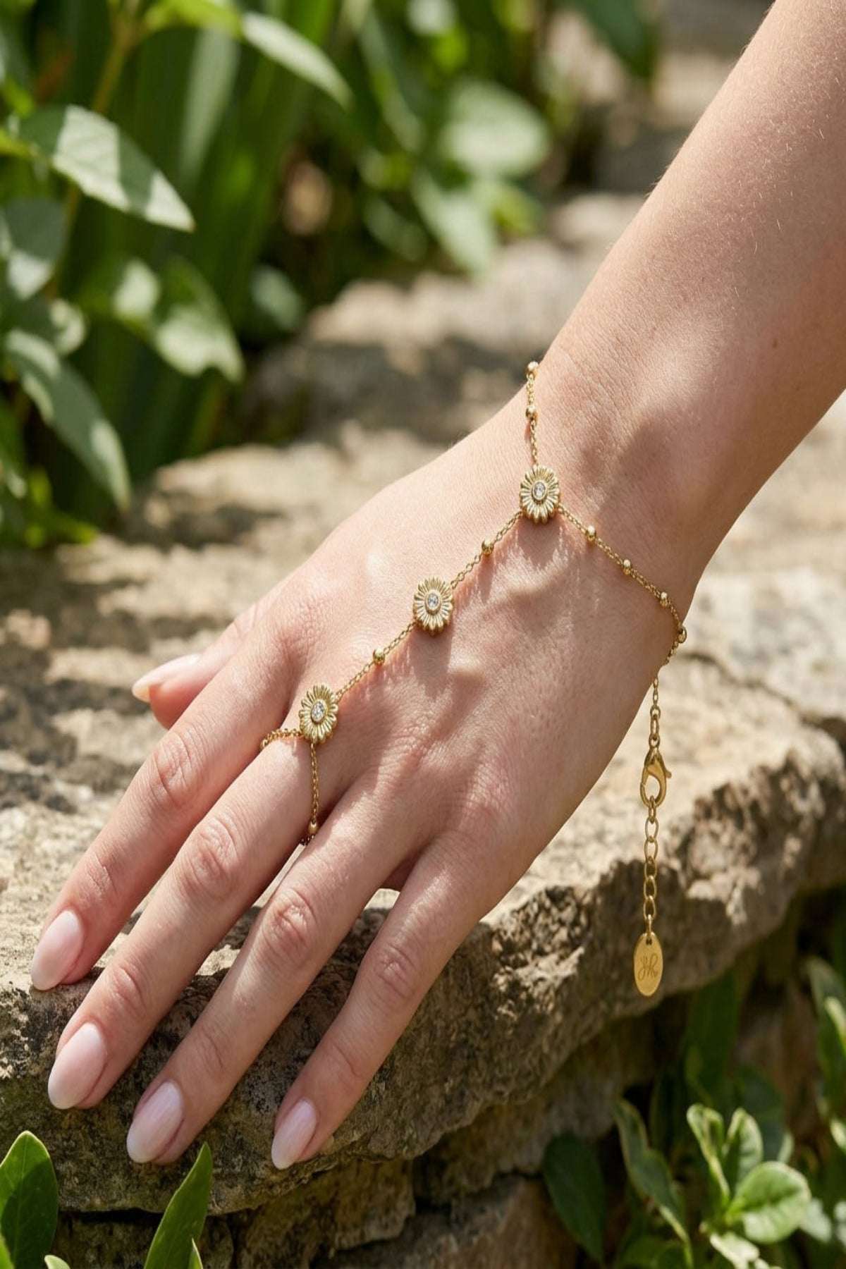 Petite floral finesse stainless steel bracelet on a model's wrist outdoors, showcasing the lobster clasp and subtle floral details in natural daylight.