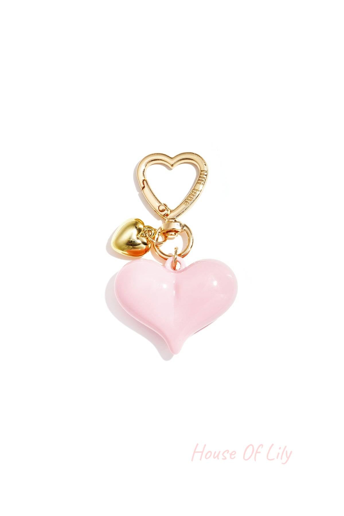 Single pastel pink acrylic heart bag charm with gold heart clasp and mini gold heart pendant on white background