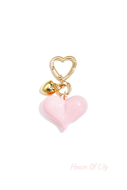 Single pastel pink acrylic heart bag charm with gold heart clasp and mini gold heart pendant on white background