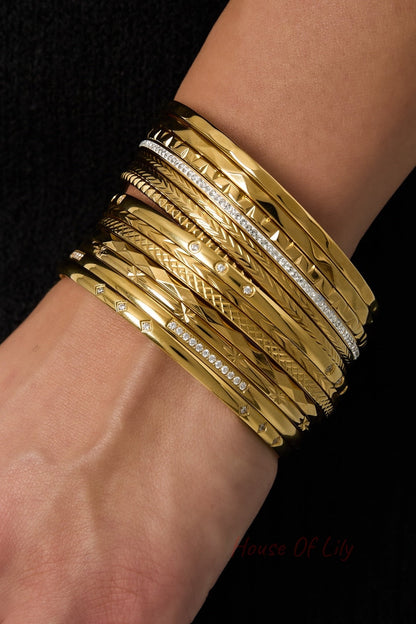 Wrist wearing multiple gold textured and rhinestone bangles stacked together