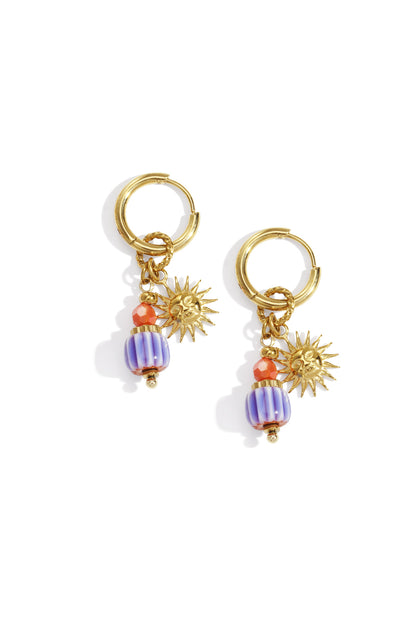 Gold tone hoop earrings with dangling sun charms and blue-orange glass beads laid flat on white background