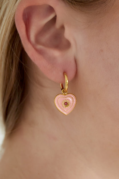 Close-up of ear wearing a gold-tone hoop earring with a soft pink heart-shaped enamel charm and beaded detailing