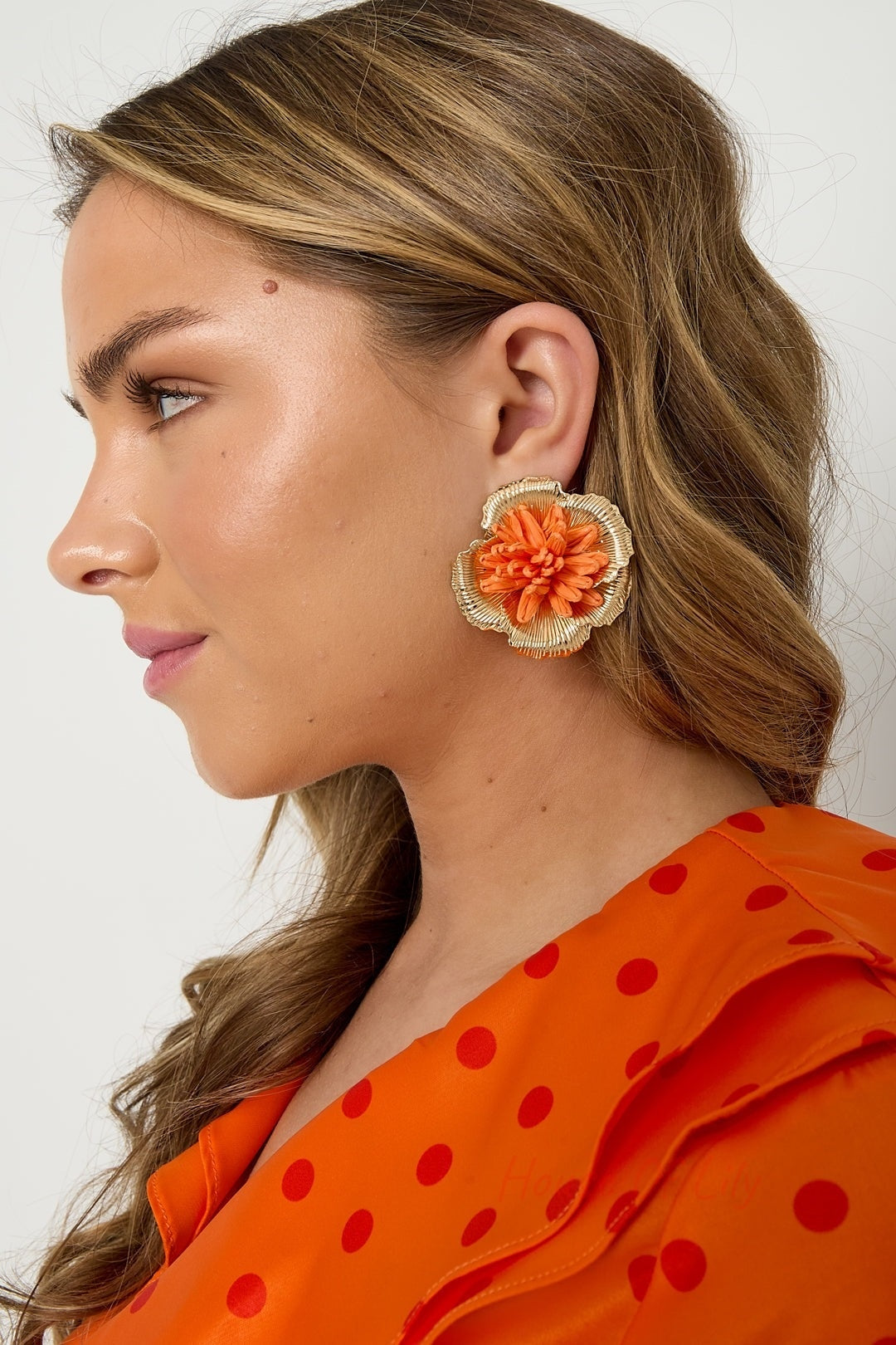 Pair of bright pink 3D raffia flower stud earrings with gold-tone metal frame on white background