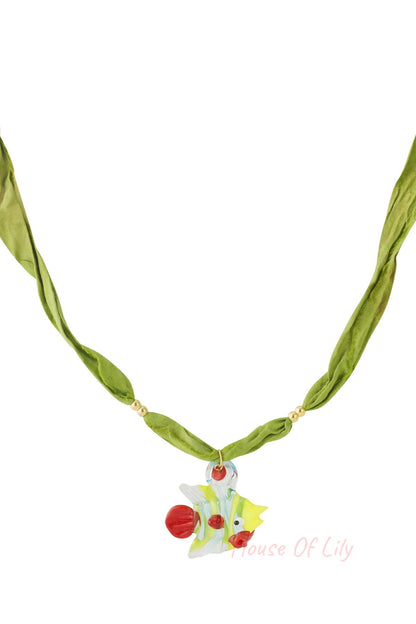 Green fabric cord necklace with a colorful glass fish pendant featuring yellow, red, and blue accents