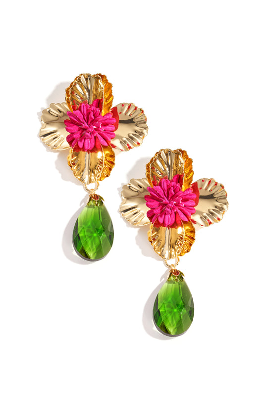 Pair of gold-toned floral drop earrings with bright pink fabric flower center and green faceted teardrop pendants on white background