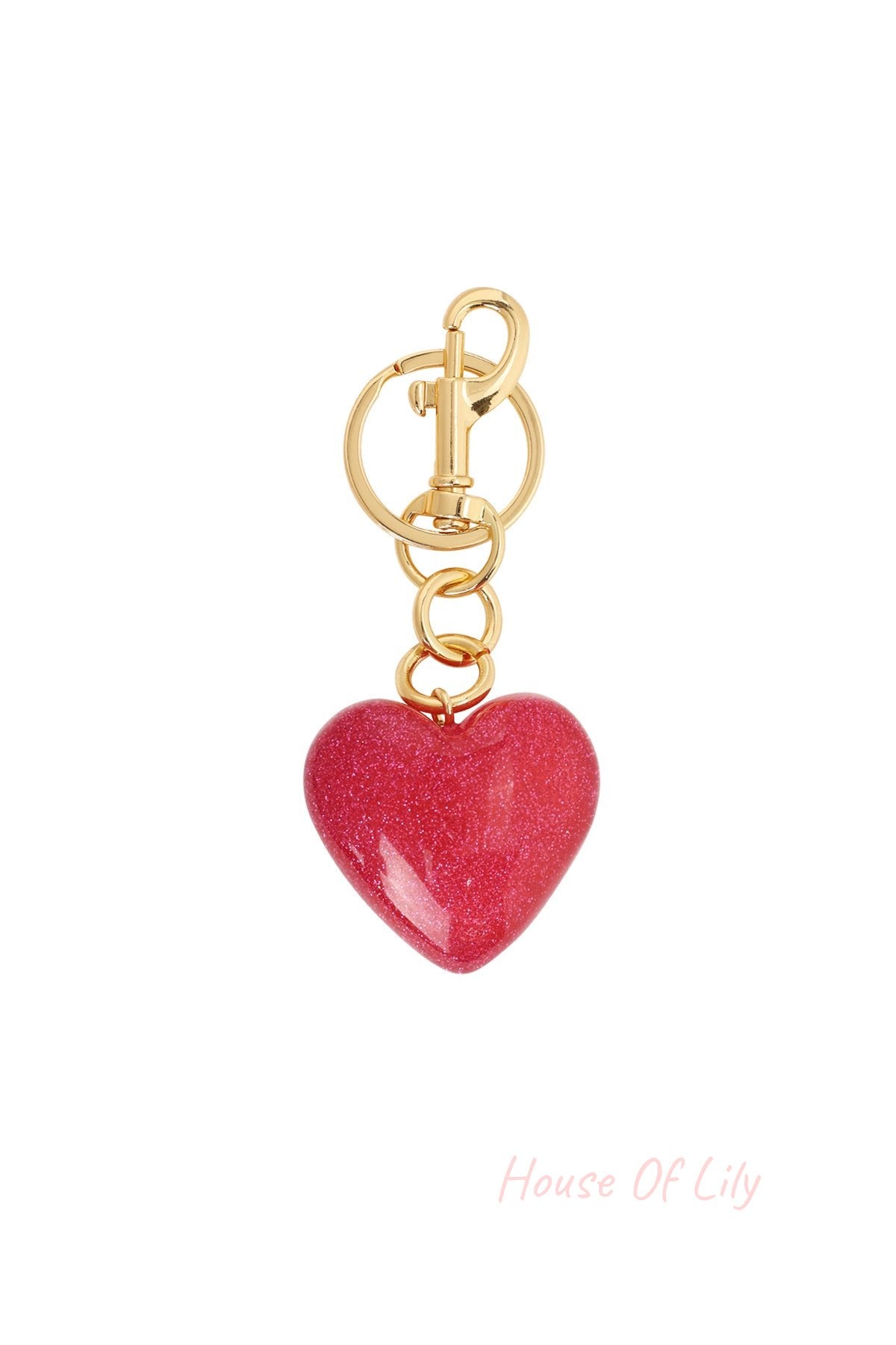 Close-up of a glittery red heart-shaped acrylic bag charm with gold alloy clasp and ring on white background.