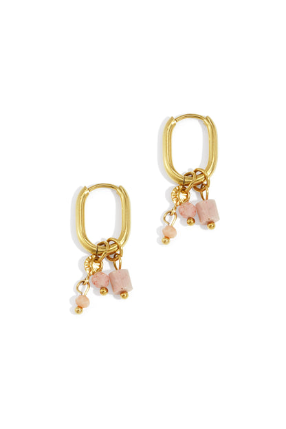 Close up shot of gold rectangular hoop earrings adorned with soft pink stone charms and gold beads on white background
