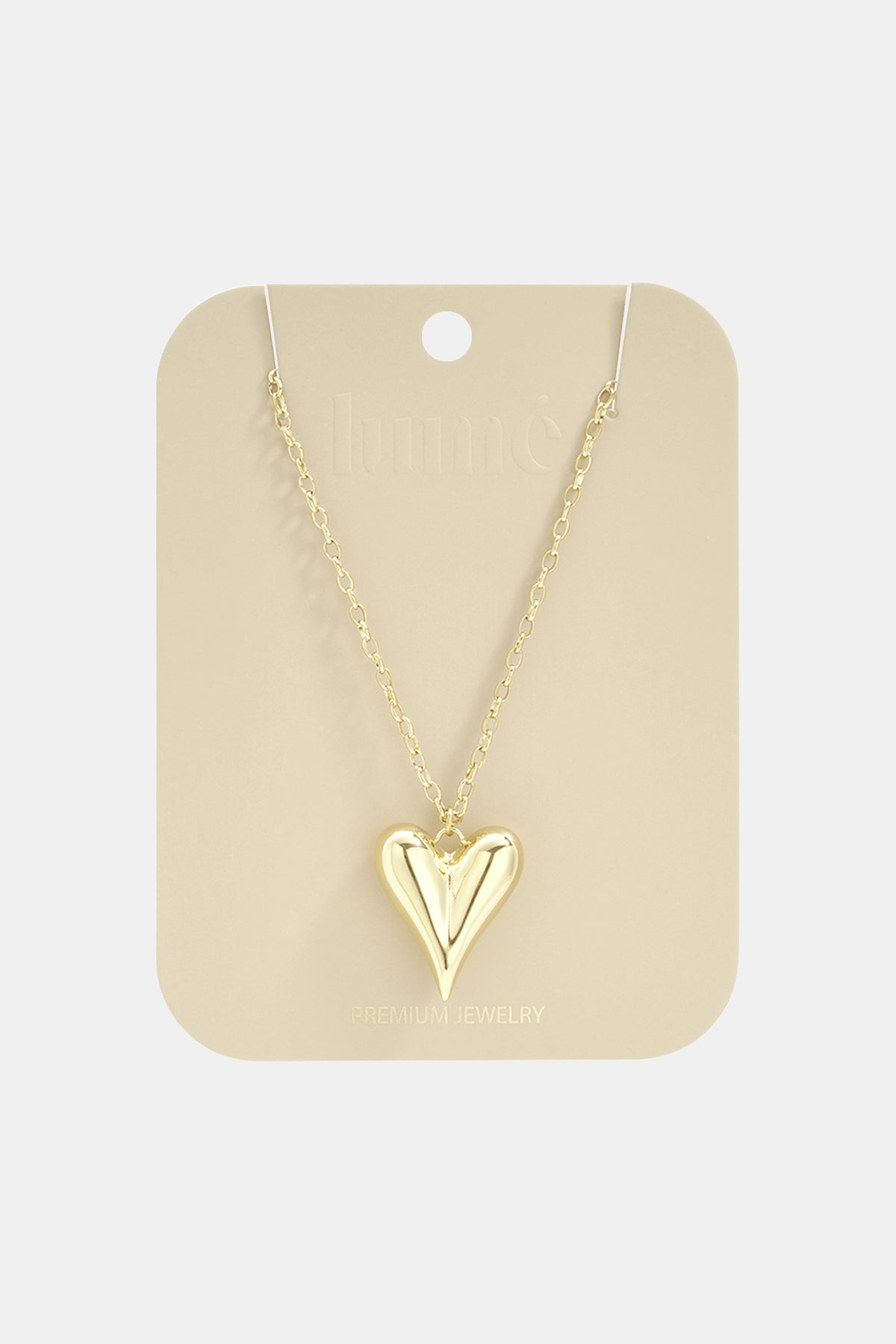Gold-toned long necklace featuring a smooth, puffed heart pendant on a delicate link chain, displayed on a card.
