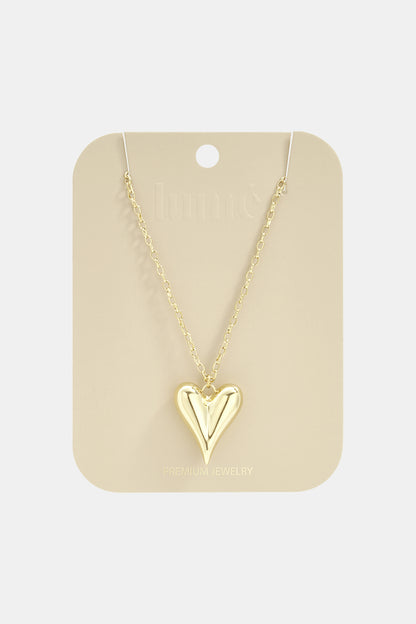 Gold-toned long necklace featuring a smooth, puffed heart pendant on a delicate link chain, displayed on a card.