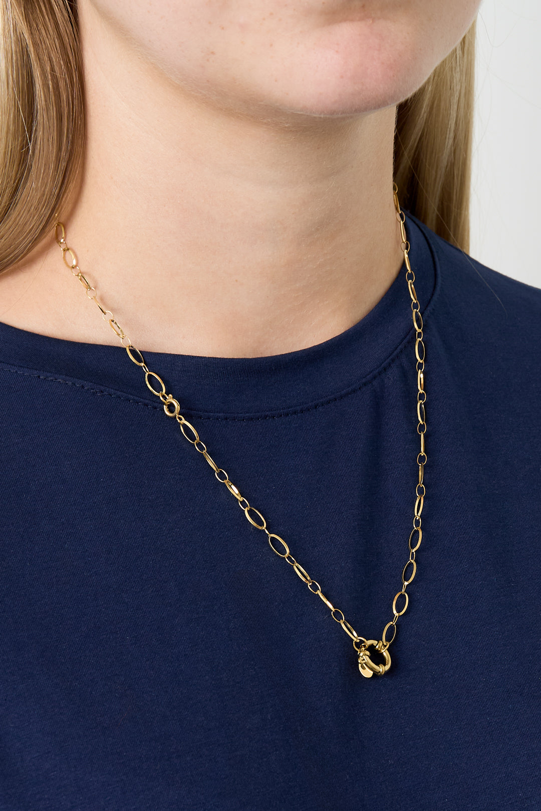 Model wearing simple gold link necklace with round clasp over a navy blue top