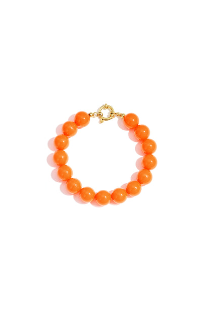 Bright orange resin bead bracelet with gold toggle clasp on white background