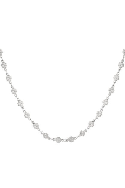Close-up of a silver-colored necklace with small clover-shaped links linked by fine chain against a white background