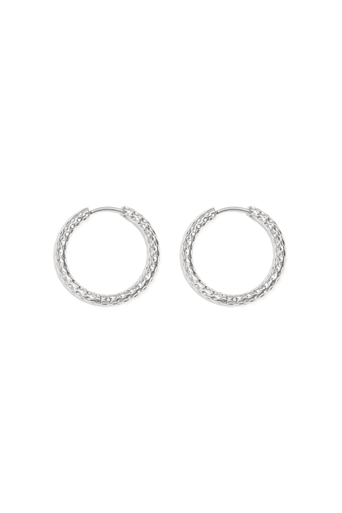 Close-up image of textured silver hoop earrings laid flat on white background