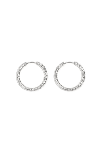 Close-up image of textured silver hoop earrings laid flat on white background