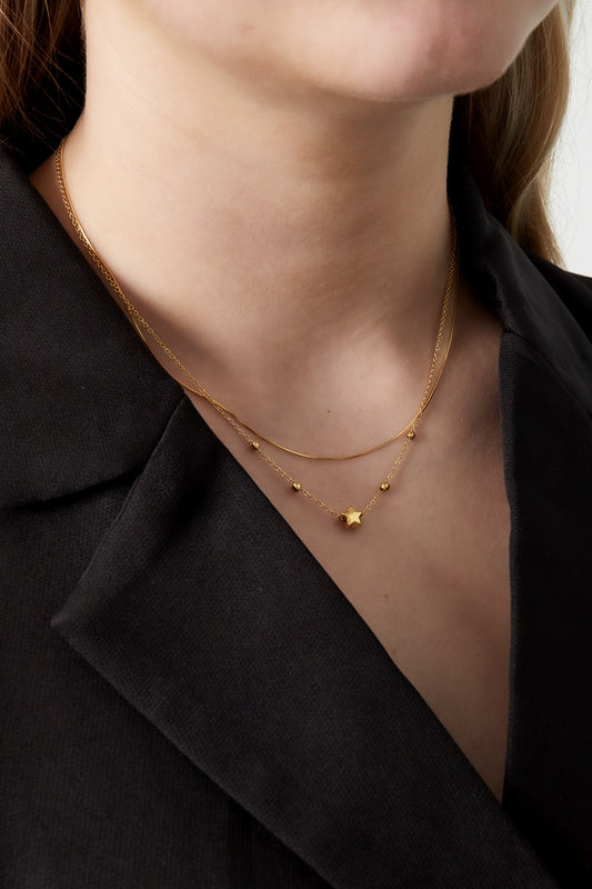 Close-up of model wearing the gold layered star necklace with a black blazer showing soft youthful style