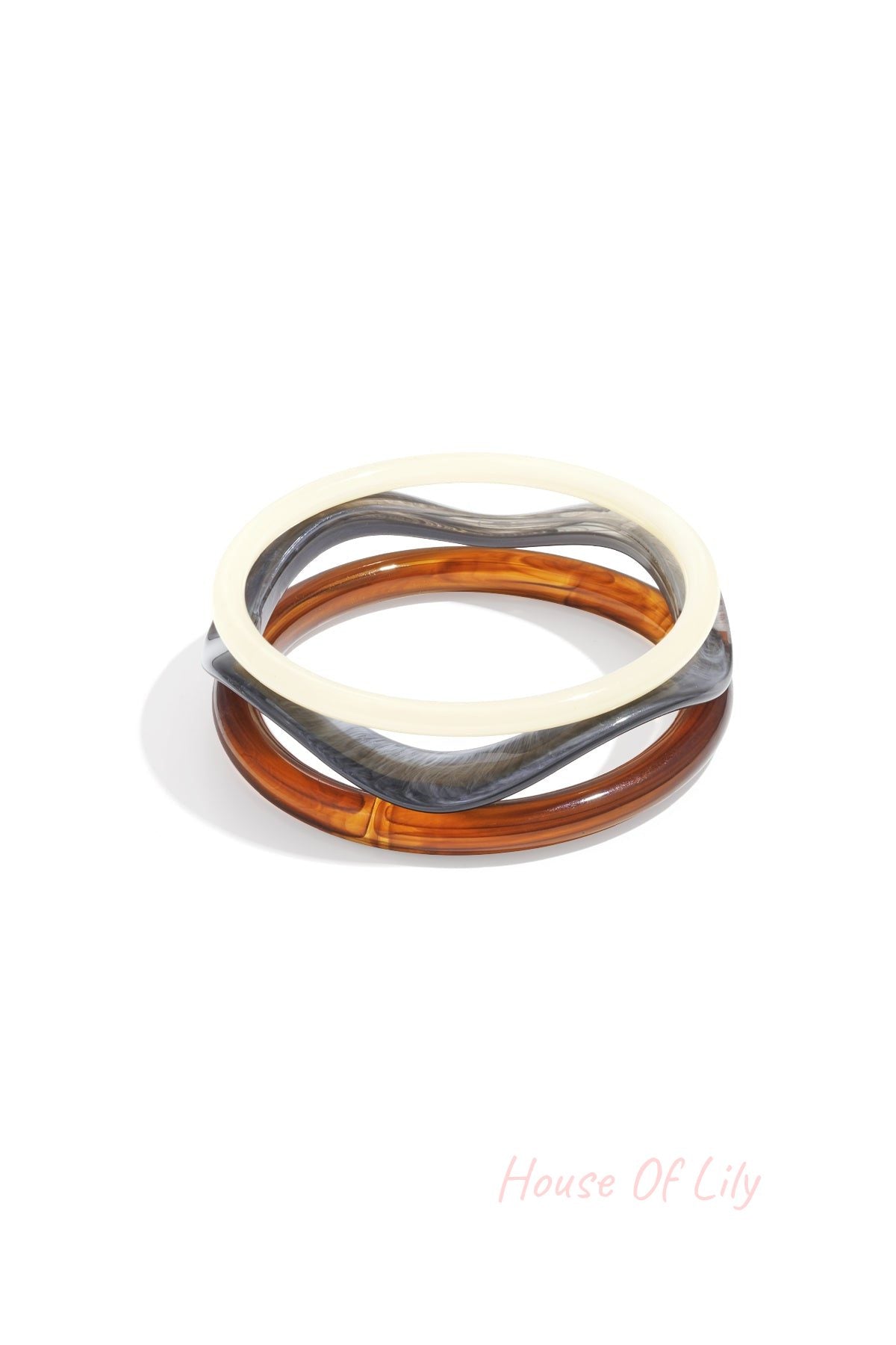 Set of three acrylic bangles in white, tortoise amber, and grey marbled colors on white background