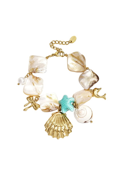 Gold-tone shell charm bracelet with natural irregular shells, turquoise starfish charm, pearl bead, and dolphin charm on white background