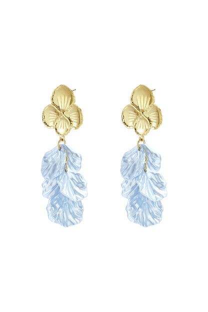 Close-up side view of woman wearing gold flower drop earrings with blue textured petals, showing delicate detail