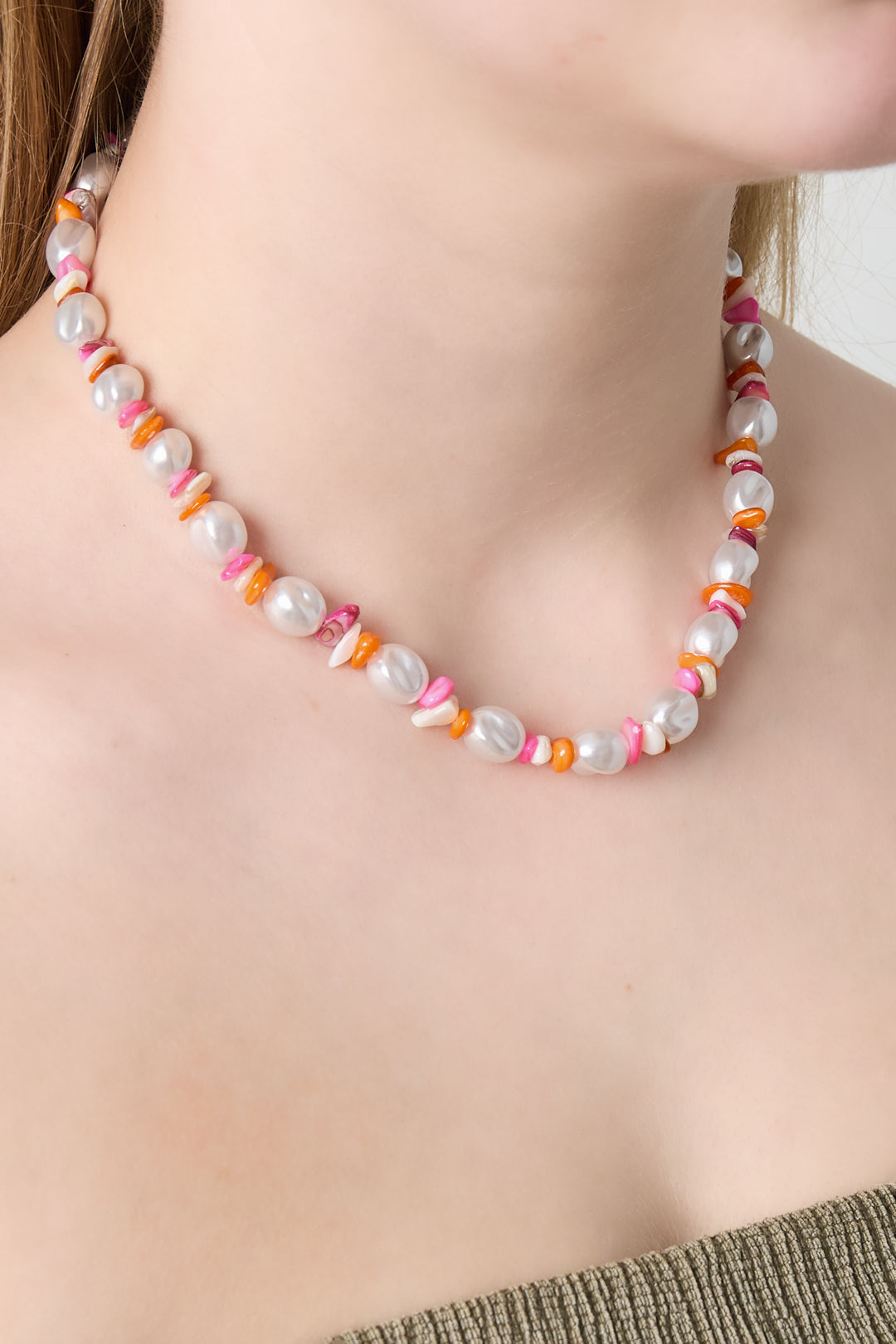 Woman wearing a colorful pearl and bead necklace close to the neck