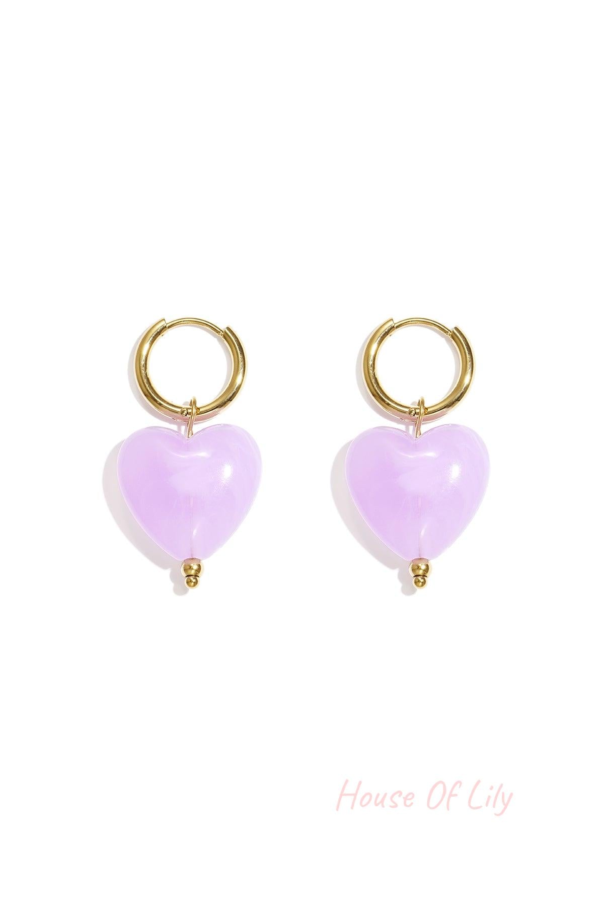 Pair of gold hoop earrings with amber brown glossy resin heart pendants on white background