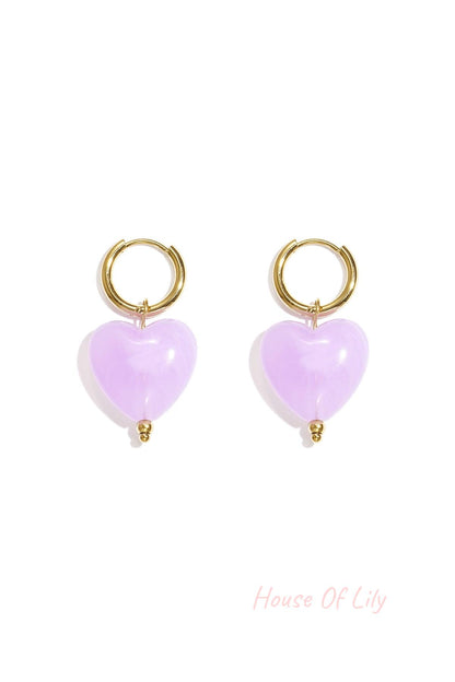 Pair of gold hoop earrings with amber brown glossy resin heart pendants on white background
