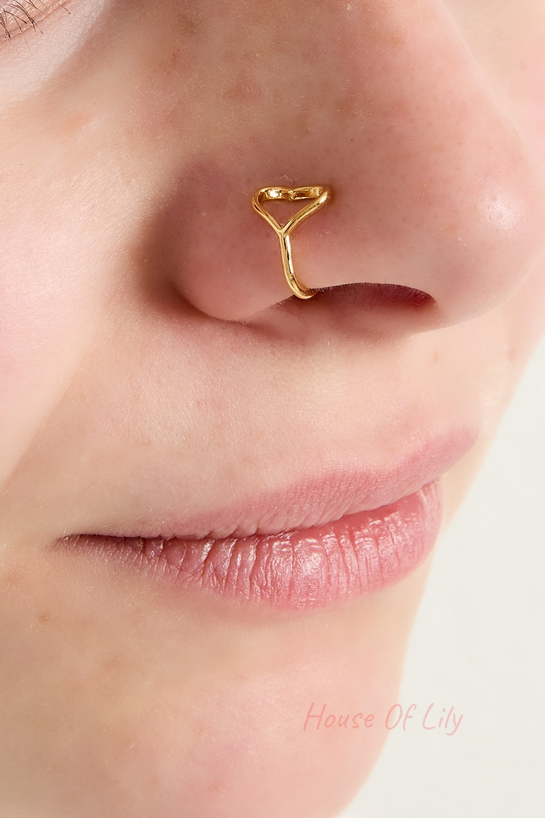 Close-up of a model wearing a gold-tone heart-shaped open ring on her nose