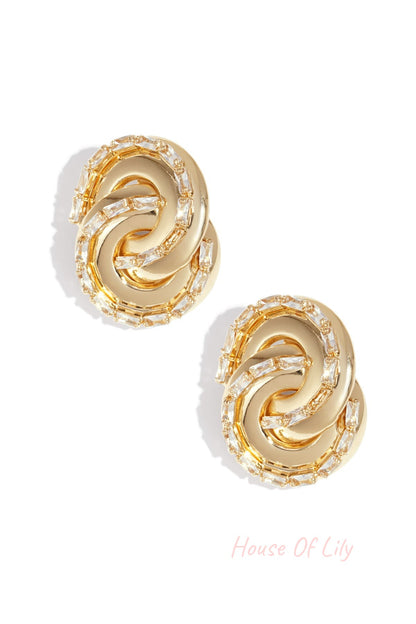 Gold-toned twisted chain stud earrings with baguette-cut crystals on white background
