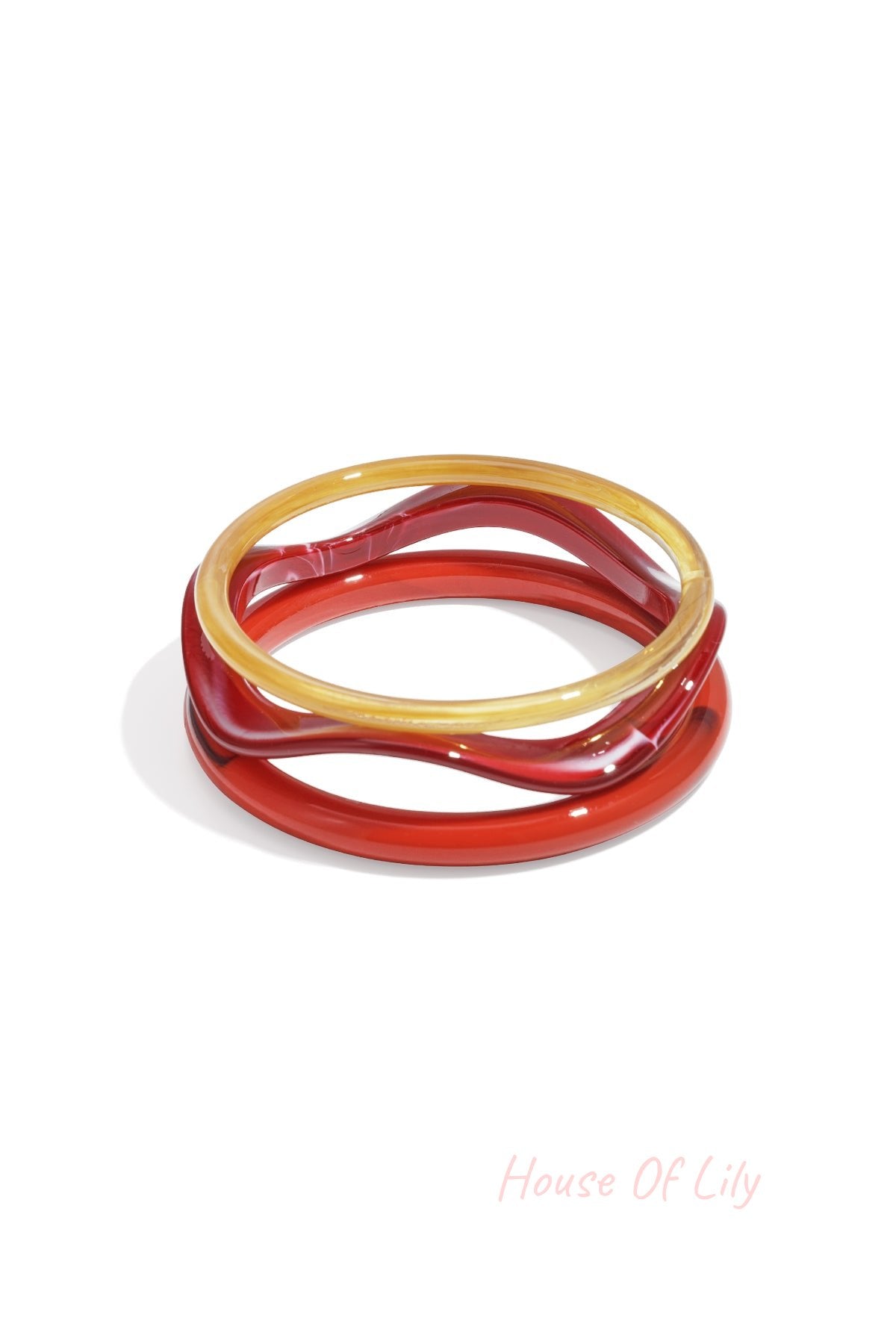 Three wave-shaped acrylic bangles in pink, purple, and amber tortoise shades on white background