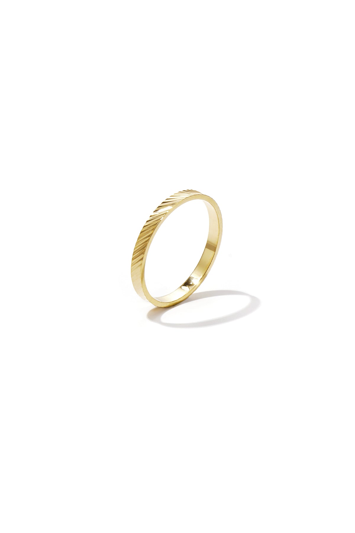 Close-up of a sleek gold minimalist ring with diagonal textured design on white background