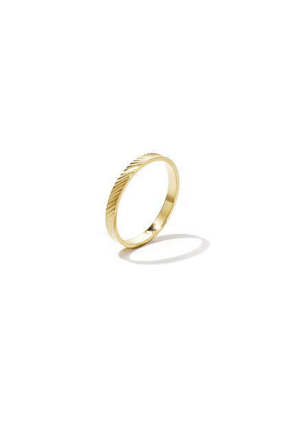 Close-up of a sleek gold minimalist ring with diagonal textured design on white background