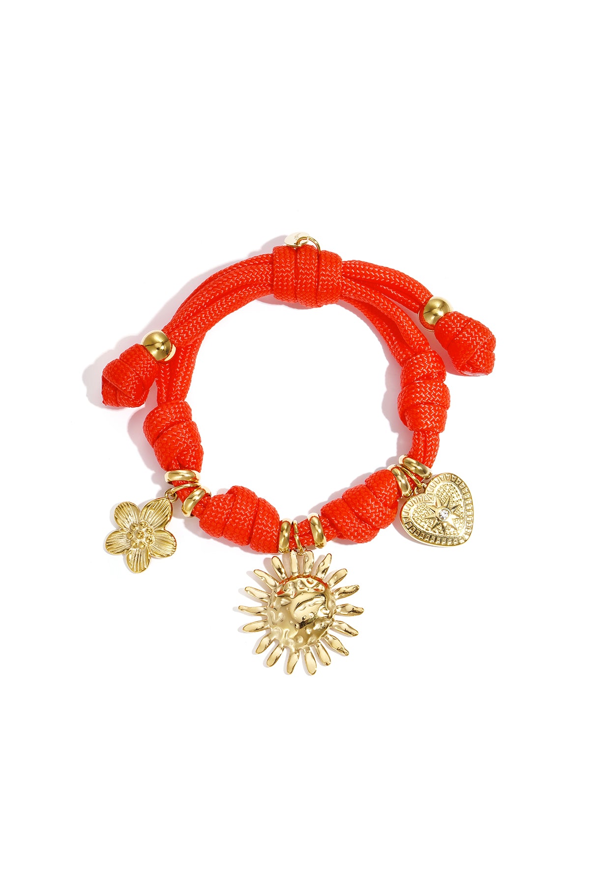 Coral rope charm bracelet with three different gold charms including heart, sun, and flower on a white background