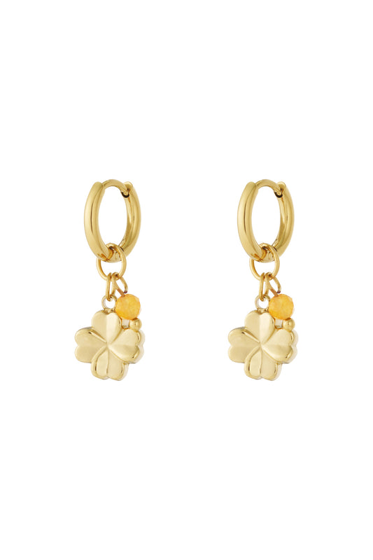 Gold hoop earrings with small four-leaf clover charms and yellow faceted bead accents shown on white background