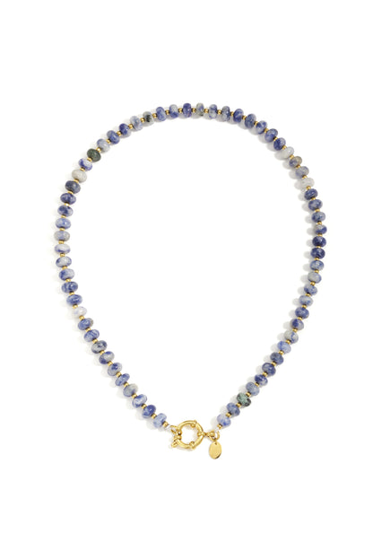 Close-up of a blue and white stone beaded necklace with small gold beads and toggle clasp