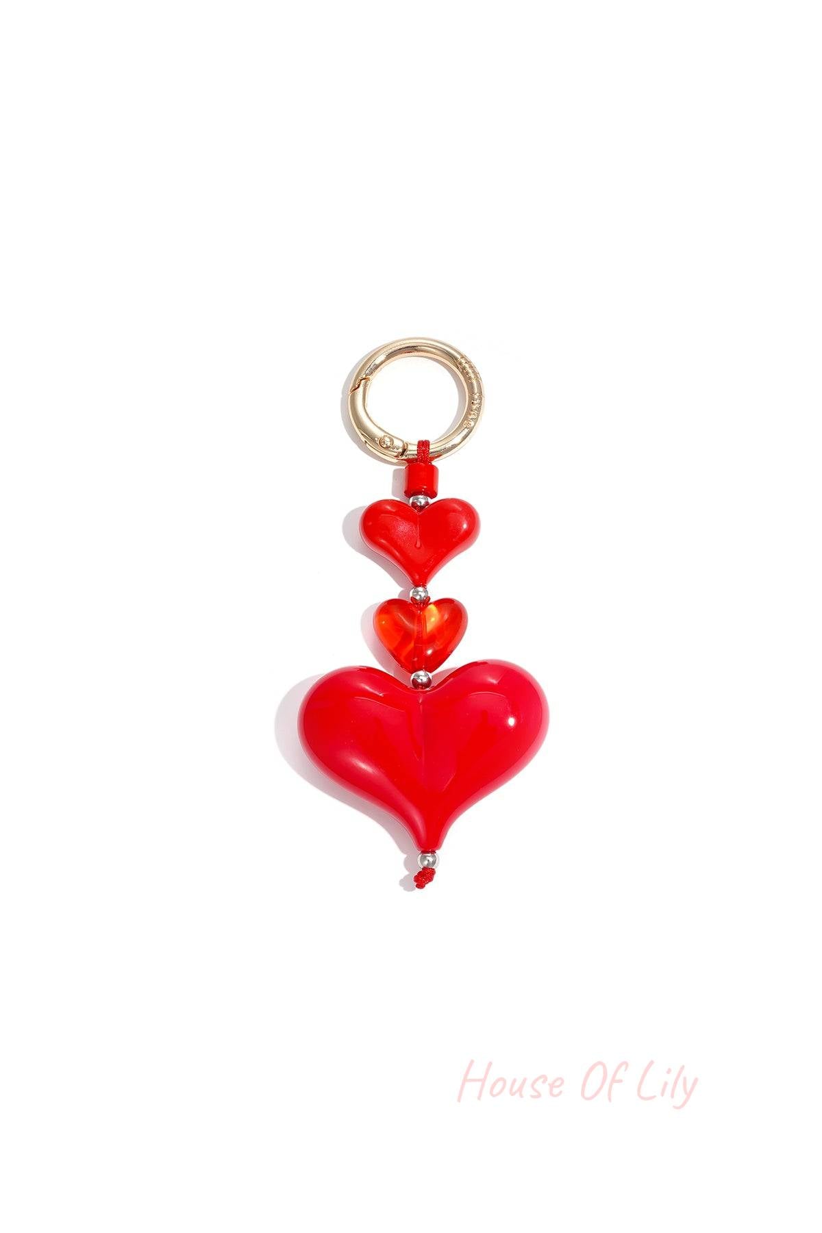 Red heart charm keychain with three varying sized acrylic hearts and gold-tone clasp on white background