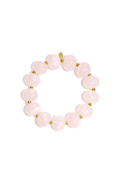 Close up of soft pink marbled beaded stretch bracelet with gold spacer beads on white background