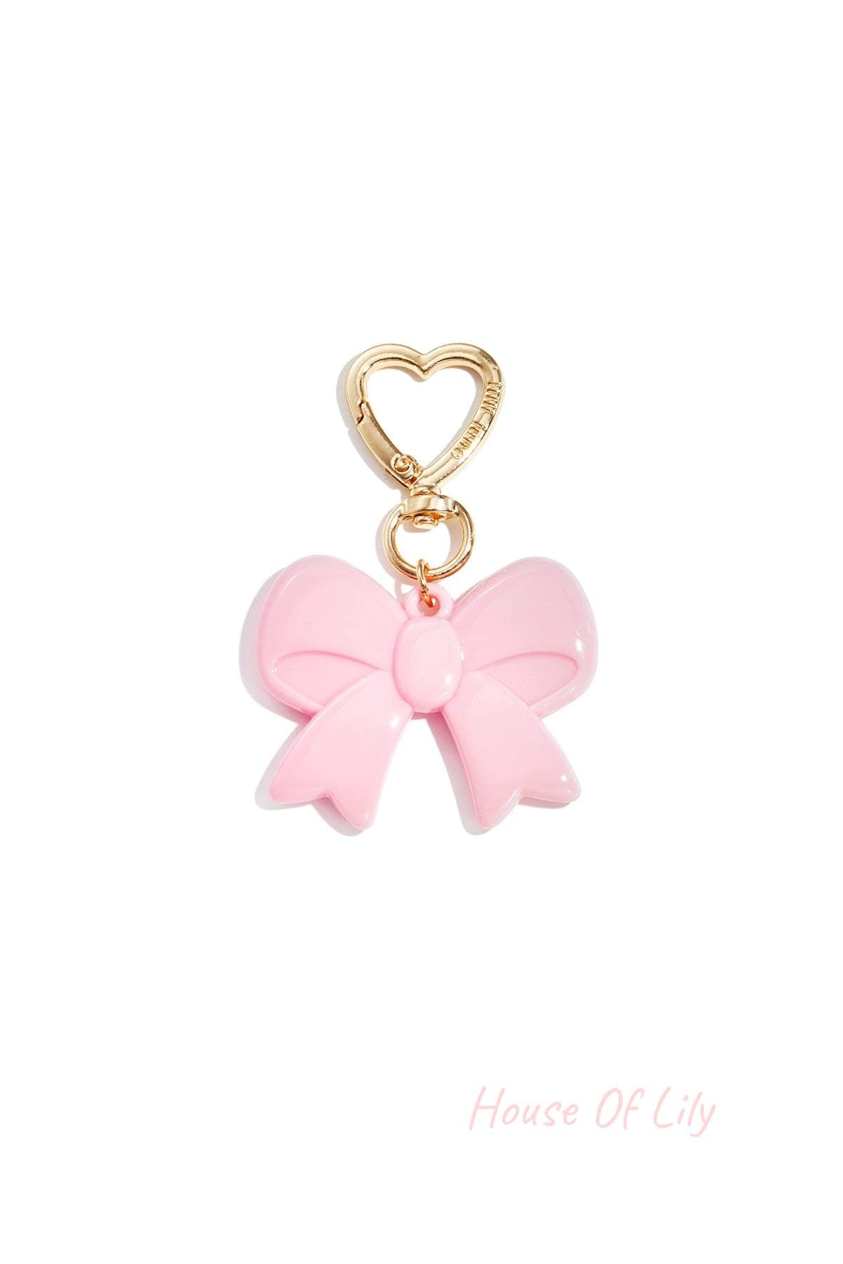 Light pink acrylic bow keychain with heart-shaped gold clasp on white background