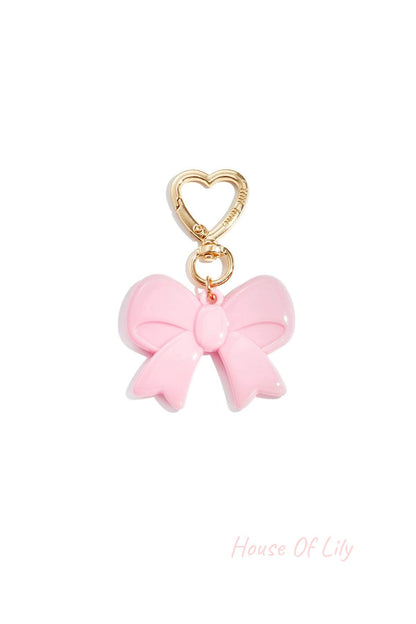 Light pink acrylic bow keychain with heart-shaped gold clasp on white background