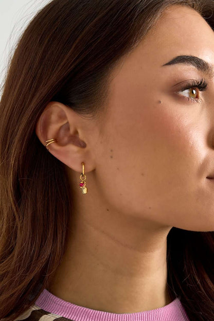 Model wearing Pineapple Aura Drops: a gold hoop earring featuring a dainty pineapple charm with a small pink gemstone.