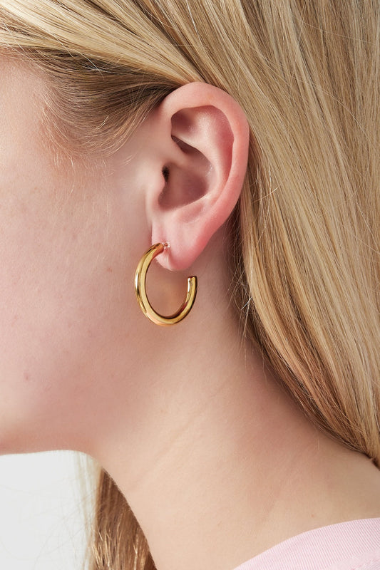 Close-up of a woman wearing a chunky gold hoop clip earring showing fit and style