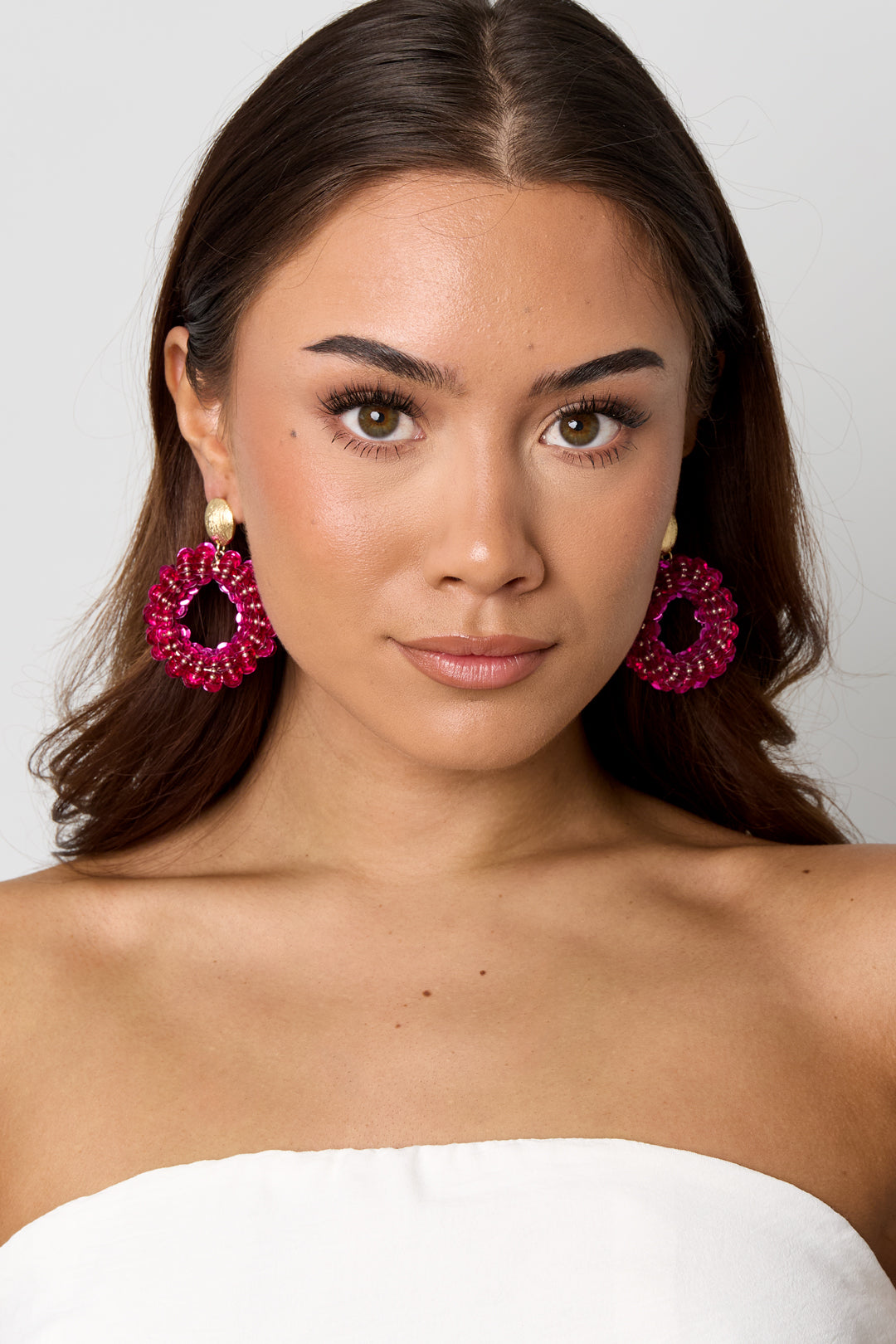 Model wearing Drip In Disco earrings: circular hot pink sequin hoops with small gold stud tops.