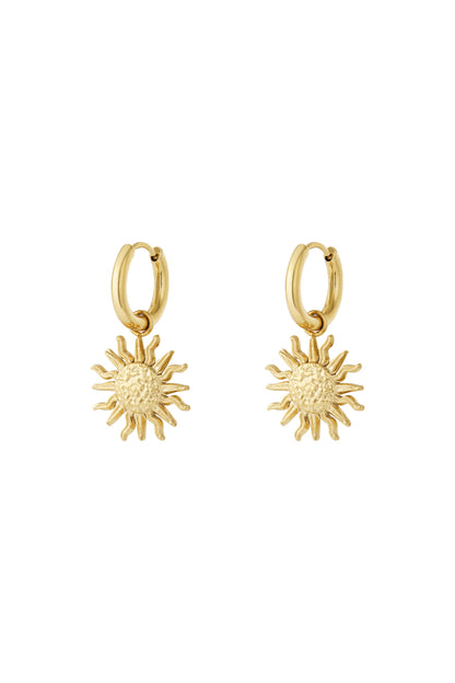 Pair of gold drop hoop earrings with textured sun charm pendants on white background