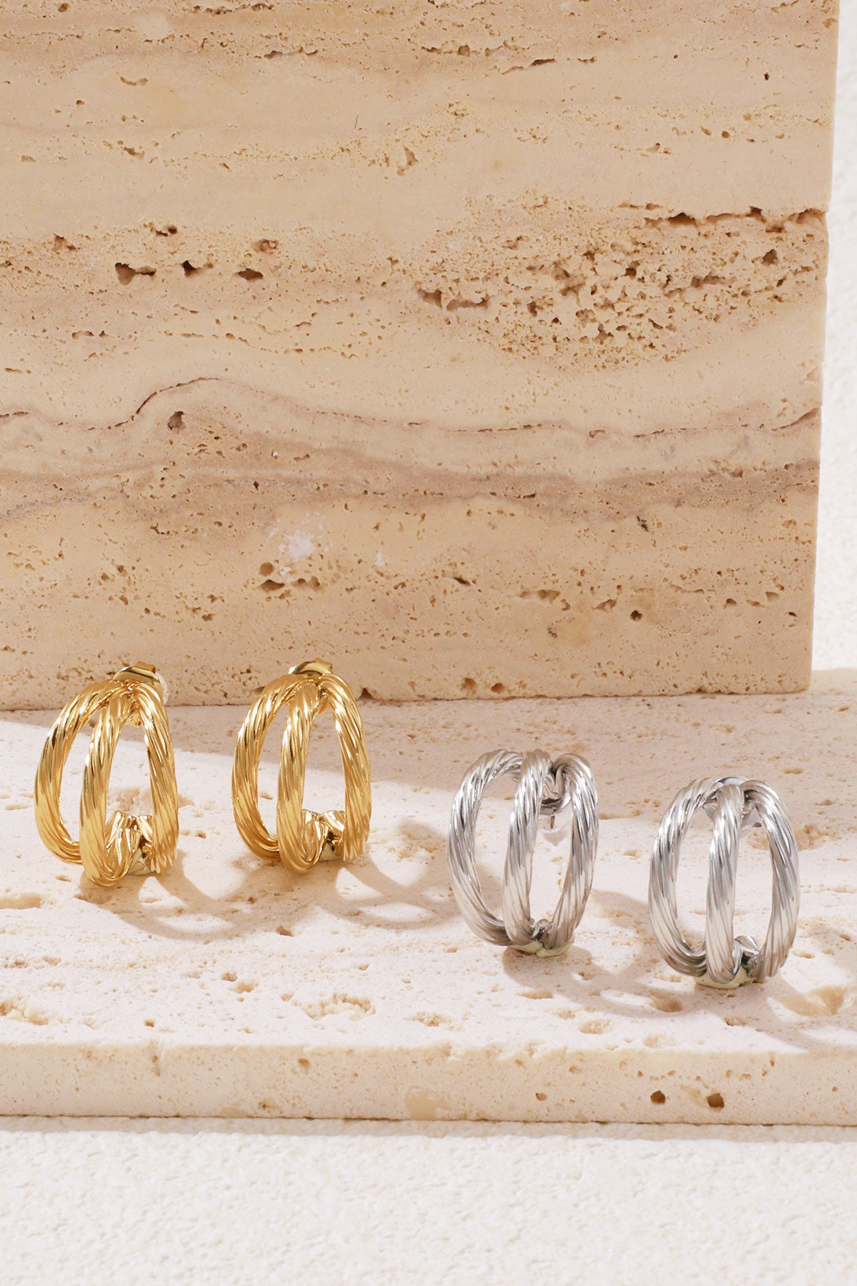 Gilt Twist Hoops: two pairs of small, double-layered twisted metal hoop earrings in gold and silver on a stone base.