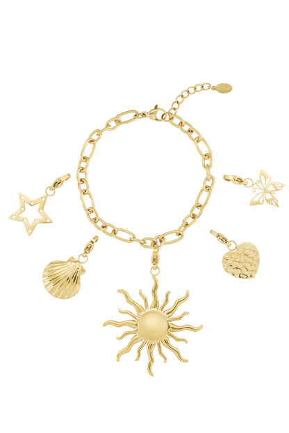 Gold charm bracelet with sun, star, butterfly, heart, and shell charms on white background