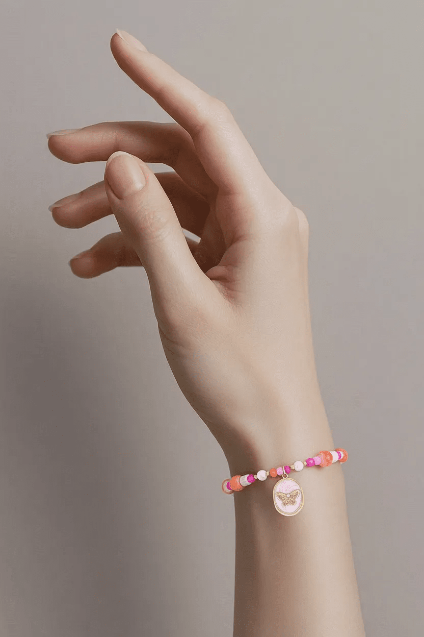 Beaded butterfly charm bracelet featuring pink and orange beads with a gold, round pink enamel butterfly pendant.