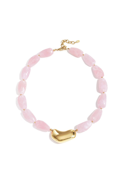Chunky beaded necklace with soft pink marbled beads and glossy gold asymmetrical centerpiece displayed on a white background