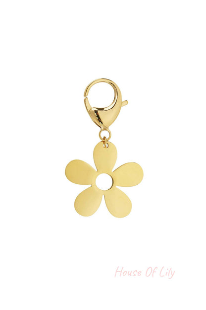 Close-up of a gold flower charm with five petals and a circular center attached to a lobster clasp on white background
