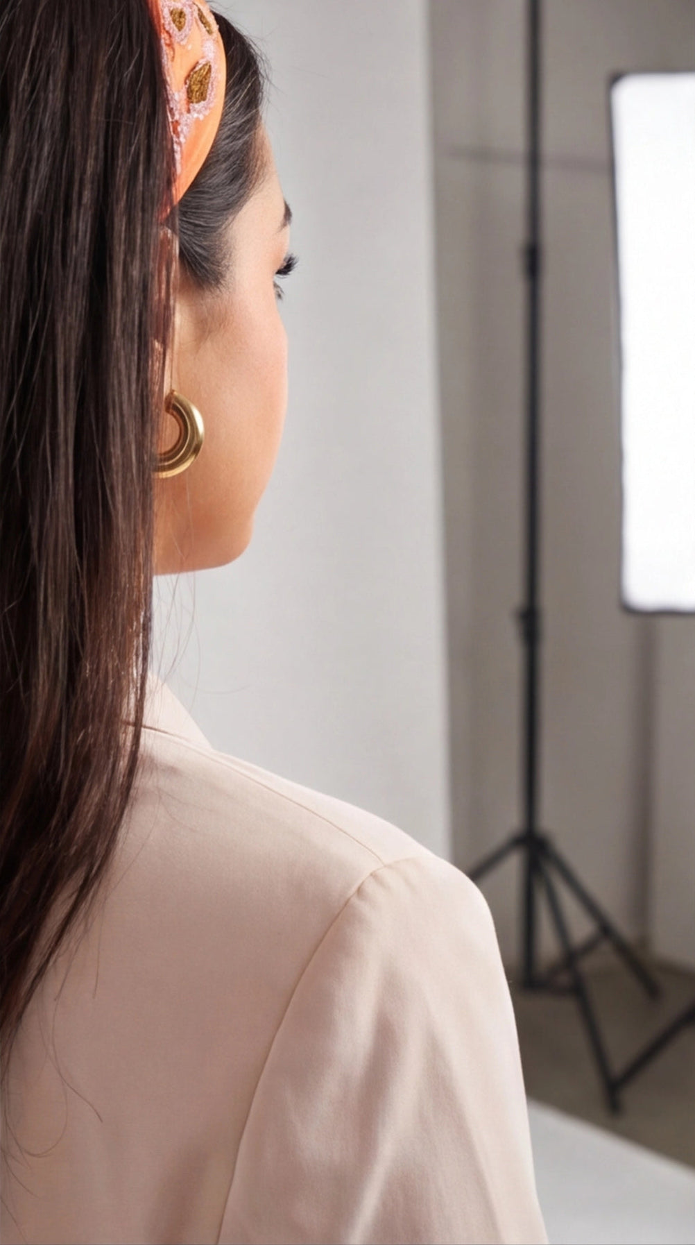Side profile of a woman wearing minimalist, polished gold hoop earrings with a thick, rounded design.