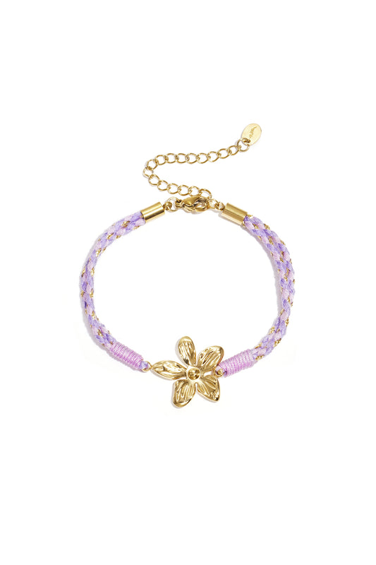 Close-up of lavender braided rope bracelet with gold flower charm and adjustable chain clasp on white background