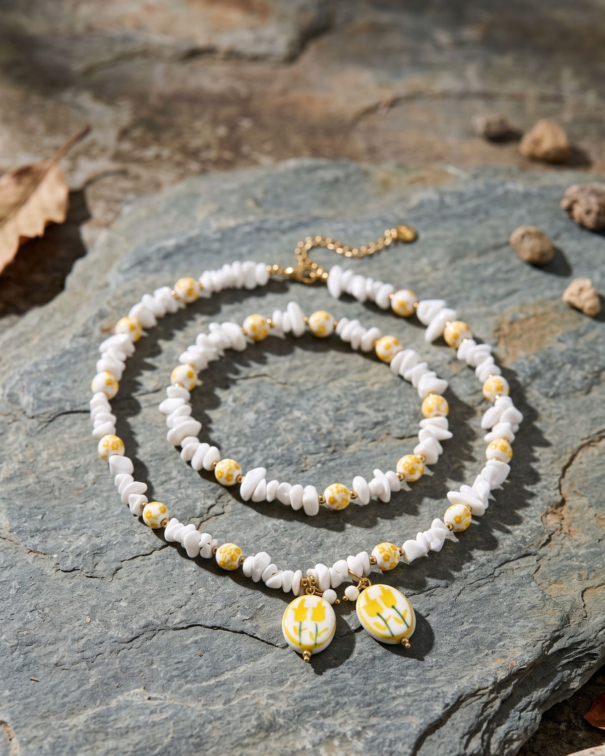 Charming yellow flower beaded necklace made with ceramic and crystal displayed on a weathered slate stone surface.